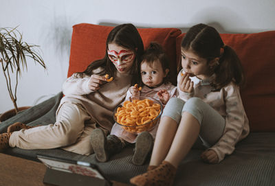 Portrait of siblings sitting on sofa at home