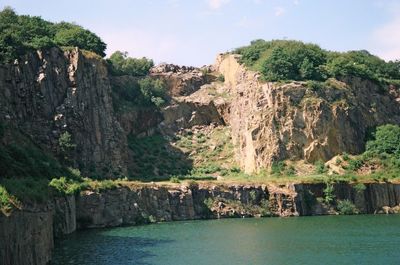 Scenic view of lake by cliff against sky