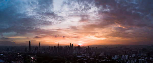 Panoramic view of city against cloudy sky during sunset