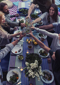 High angle view of multi-ethnic friends toasting drinks at dinner table in yard