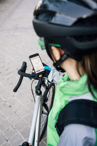 From above anonymous courier examining route on gps map before riding bicycle on city street