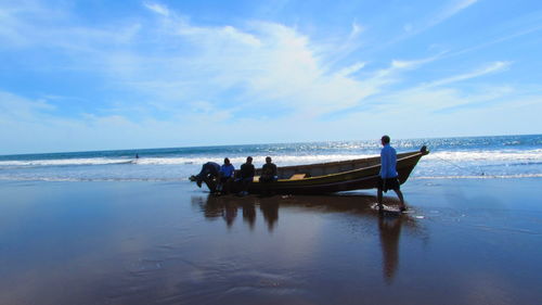 People sitting on beach against sky