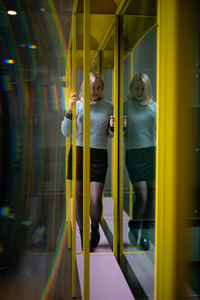 Full length of woman standing on bench by glass window