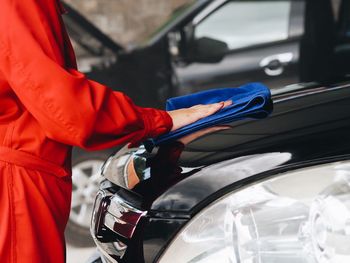 Midsection of mechanic polishing car in workshop