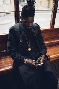 Man holding mobile phone while sitting in bus