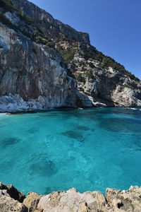 Scenic view of sea and rocks against clear blue sky