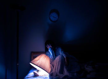 Woman sitting on bed at home