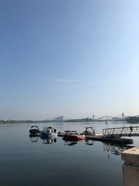 Boats moored in sea against clear sky