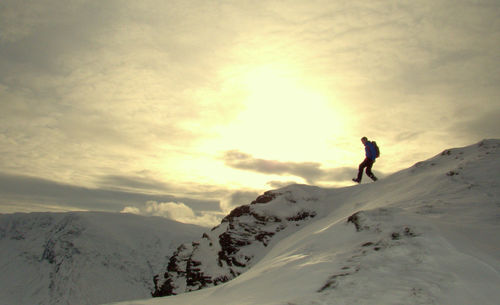 Silhouette person on snowcapped mountain against sky during sunset