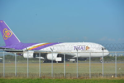 Airplane on airport runway against sky