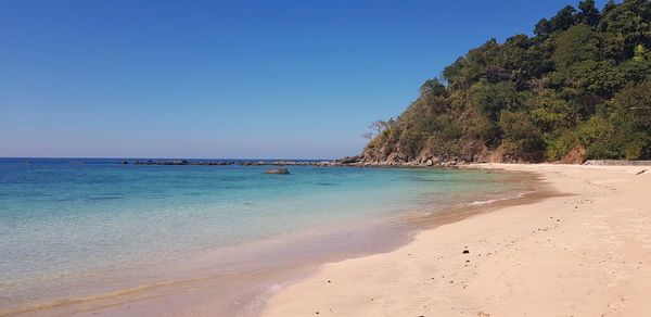 Scenic view of beach against clear blue sky