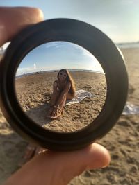 Portrait of woman looking through loop at beach