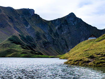 Scenic view of lake by mountains against sky