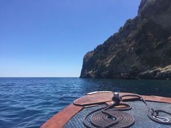 Close-up of boat sailing on sea against clear blue sky