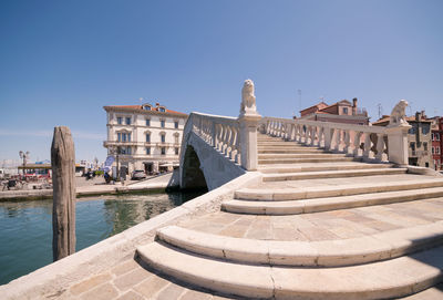 View of canal amidst buildings against clear blue sky