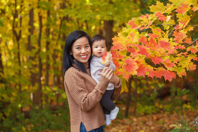 Portrait o smiling young woman with daughter in park