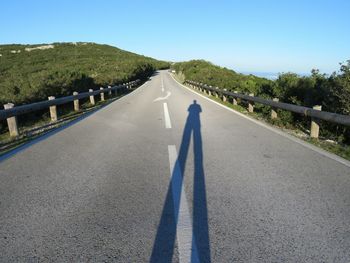 Shadow of man on mountain road during sunny day