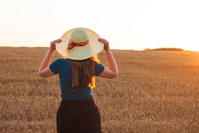 Adorable young girl in summer wheat field in straw hat. woman with long hair countryside sunset