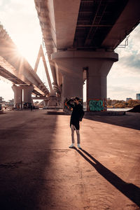 Full length of woman standing on bridge in city against sky