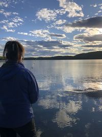 Rear view of woman looking at lake against sky