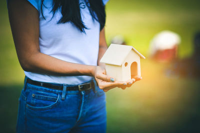 Midsection of woman holding model house