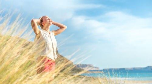 Woman with arms raised hair against sky