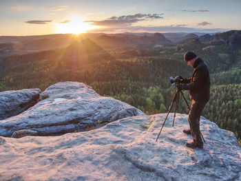 Amateur photographer prepare equipment for taking photos with tripod and camera. spring sunrise