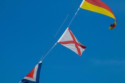 Low angle view of flags against blue sky