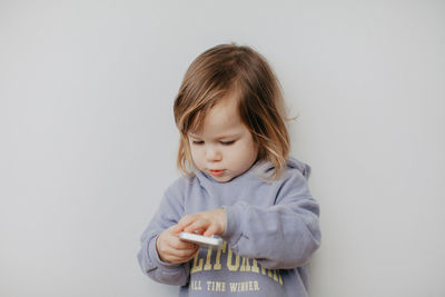 Portrait of cute girl looking away while standing against white background