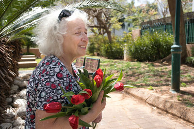 Happy elderly woman with a bouquet of red tulips.