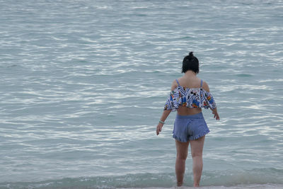 Rear view of young woman standing in sea
