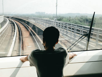 Rear view of woman sitting on bridge