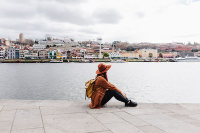 Side view of man sitting against buildings in city