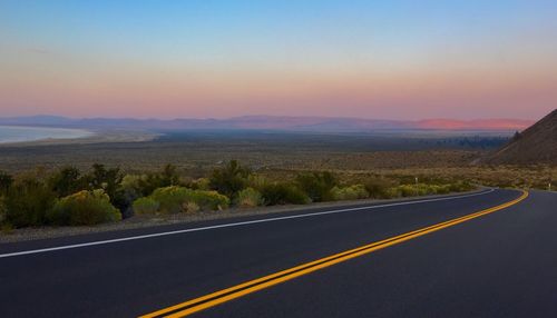 View of country road against sky during sunset