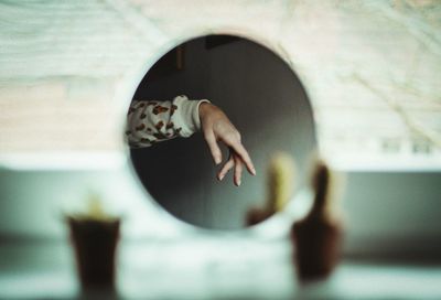 Reflection of person hand on mirror seen through hole