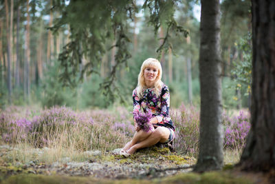 Portrait of smiling young woman sitting in forest