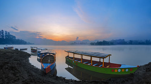 Boat moored at beach against sky during sunset