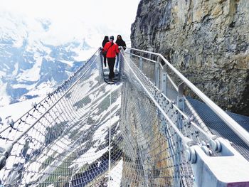 Man crossing tightrope by cliff during winter