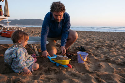 Father and child sitting at the beach in the sunset