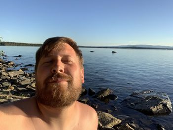 Portrait of bearded man enjoying the sun by a lake.