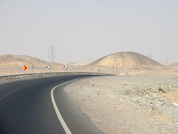 Vehicles on road by suspension bridge against clear sky