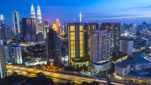 Illuminated modern buildings in city against sky at night