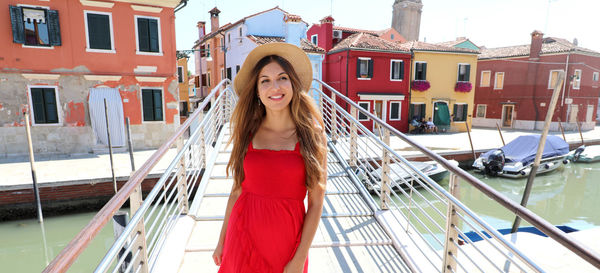 Close-up of smiling young woman on footbridge against building