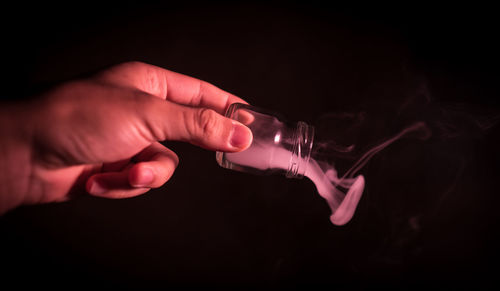 Midsection of person holding hands against black background