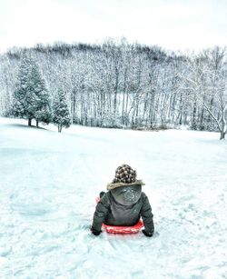 Person sledding on snow covered mountain