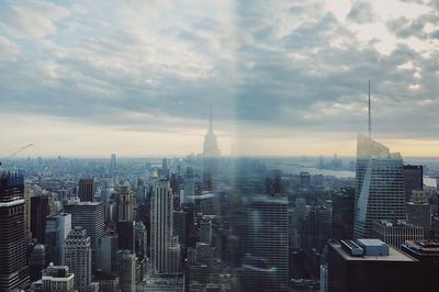 Aerial view of buildings in city against cloudy sky