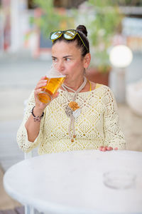 Portrait of woman drinking beer at beach cafe