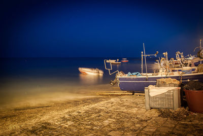 Boats moored at harbor against clear sky at night