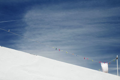 Low angle view of clothesline on wall against sky