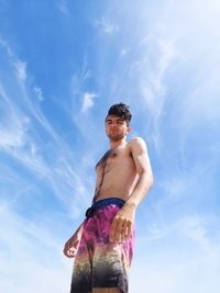 Low angle view of shirtless man standing against sky